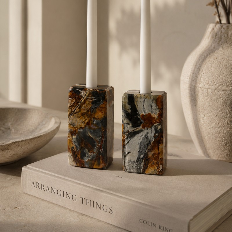 Two polished stone candle holders with taper candles resting on an open book